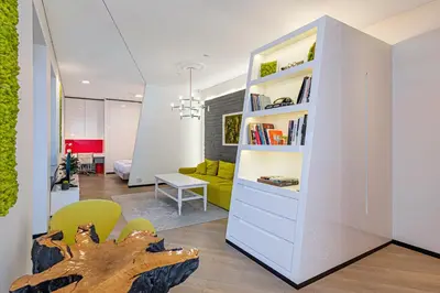 a living room with a book shelf and a couch at Modern White Moss Apartment Kaunas Center in Kaunas