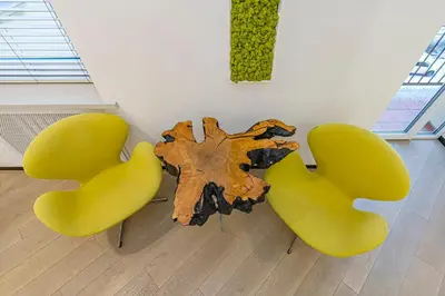 two yellow chairs sitting next to a table with a tree stump at Modern White Moss Apartment Kaunas Center in Kaunas