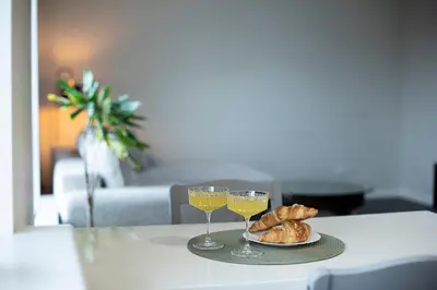 two glasses of wine and croissants on a table at Spacious and Modern Apartment with Free Parking in Vilnius