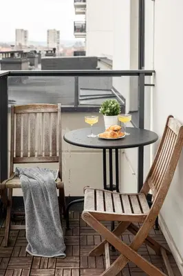 a table on a balcony with two glasses of wine at Spacious and Modern Apartment with Free Parking in Vilnius