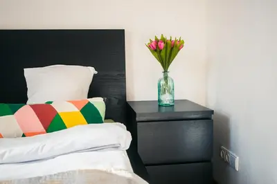 a vase of flowers on a table next to a bed at V 18 - Superior & Great views to Vokieciu street in Vilnius