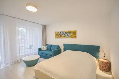 a bedroom with a bed and a blue chair at Snow apartment in Druskininkai