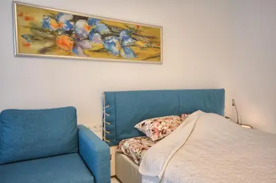 a bedroom with a bed and a blue chair at Snow apartment in Druskininkai