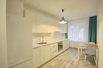 a kitchen with white cabinets and a table with a chair at Snow apartment in Druskininkai