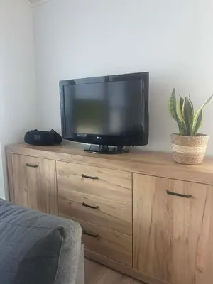 a flat screen tv sitting on top of a wooden dresser at Cozy House By VP in Anykščiai