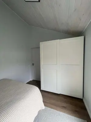 a bedroom with a white bed and a white cabinet at Cozy House By VP in Anykščiai
