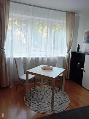 a table and chairs in a living room with a window at Jaukus būstas poilsiui in Kaunas
