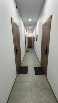 a hallway with two wooden doors and a hallway with mats at Cosy Sopenas home in Vilnius