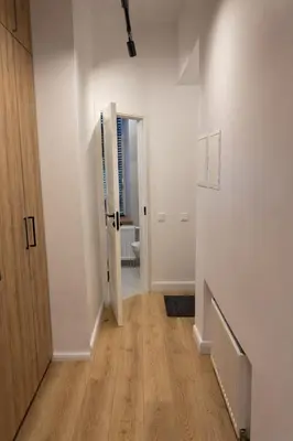 a hallway with white walls and a wooden door at Central Breeze Flat x Self Check-in in Vilnius
