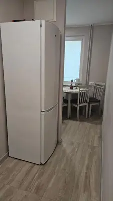 a white refrigerator in a living room with a table at Kambarių nuoma Kaune Taikos pr in Kaunas