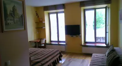 a room with two beds and windows and a television at Apartamentai Vilnius Užupis in Vilnius