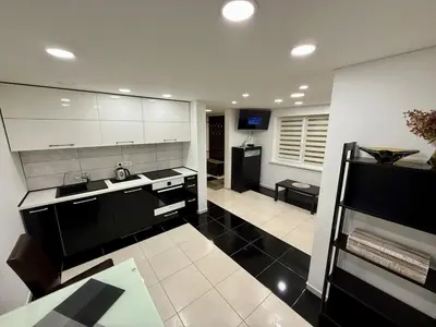 a kitchen with white cabinets and a black floor at Guest house 10 minutes from the city center in VNO
