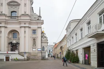 a person walking down a street next to buildings at Old Town Luxury apartment self check inn in Vilnius
