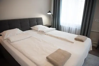 a large white bed with two towels on it at Stylish & Brand New 1 BDR Apartment in Old Town in Vilnius