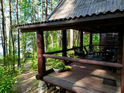 a wooden deck with a table and chairs in the woods at Vila Zara in Zarasai