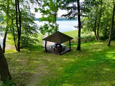 a gazebo in the middle of a field with trees at Vila Zara in Zarasai