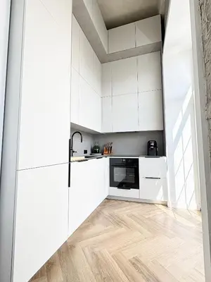 a kitchen with white cabinets and wood floors at Rooftop Terrace Loft 15 Minute Walk to Zalgiris Arena in Kaunas