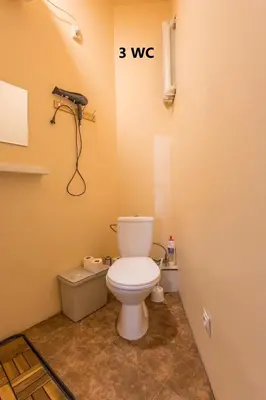 a bathroom with a toilet and a phone on the wall at Kaunas Center Hostel - Self-Check In in Kaunas