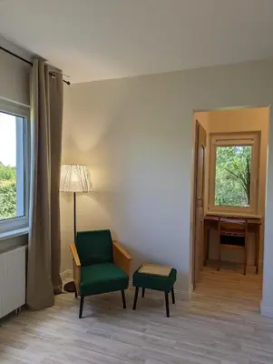a room with a chair and a desk and a window at Vila Vynuogyne in Paberžė