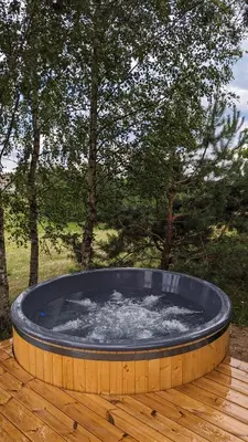 a large hot tub sitting on a wooden deck at Vila Vynuogyne in Paberžė