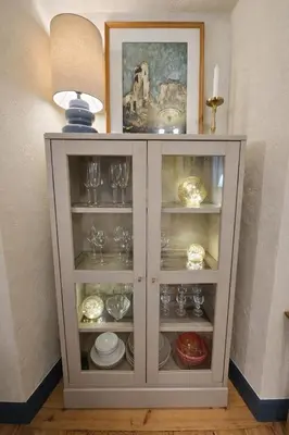 a white cabinet with plates and glasses in it at K15 History Apartments in Vilnius