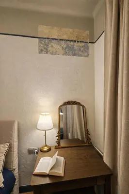 a mirror on a table with books and a lamp at K15 History Apartments in Vilnius