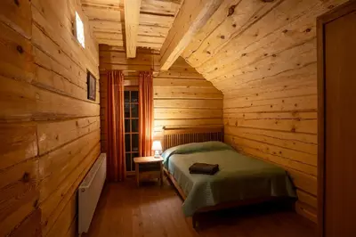 a bedroom with a bed in a wooden cabin at Močiutės sodyba in Latežeris