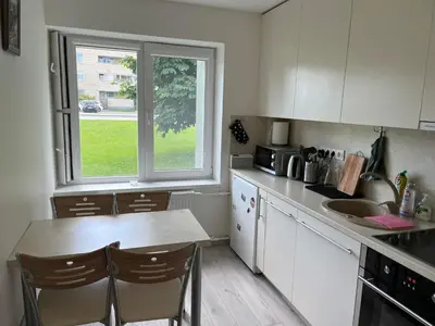 a kitchen with white cabinets and a table and a window at Kasia apartaments in Druskininkai