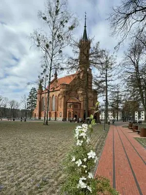 a large brick building with a clock tower and flowers at Kasia apartaments in Druskininkai