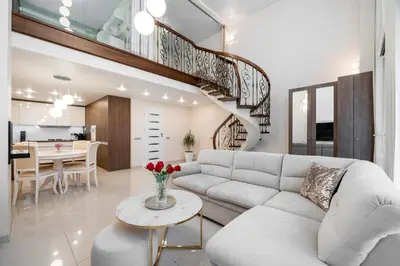 a living room with a white couch and a staircase at Loft Town Apartaments near OZAS and Akropolis in Vilnius
