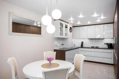 a white kitchen with a white table and chairs at Loft Town Apartaments near OZAS and Akropolis in Vilnius