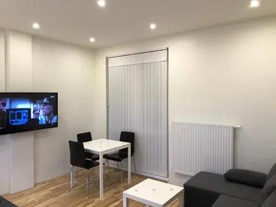 a living room with a table and a tv on a wall at B-happy Apartments in Vilnius
