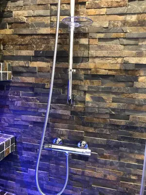 a bathroom with a stone wall with a shower at B-happy Apartments in Vilnius