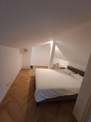 a bedroom with a white bed and a wooden floor at Vydūno apartamentai 10 in Kaunas