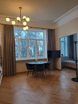 a living room with a table and chairs and a large window at Vydūno apartamentai 10 in Kaunas