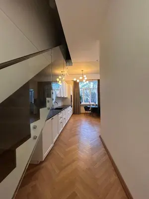 a large kitchen with white cabinets and a wooden floor at Vydūno apartamentai 10 in Kaunas