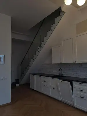 an empty kitchen with white cabinets and a staircase at Vydūno apartamentai 10 in Kaunas