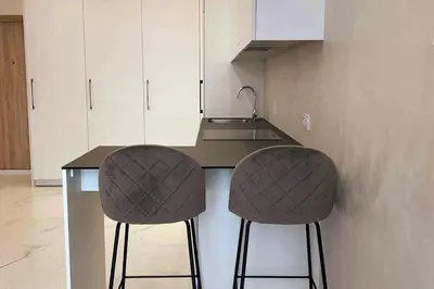 a kitchen with a counter and two bar stools at New luxury modern Apartment in Šnipiškės in Vilnius