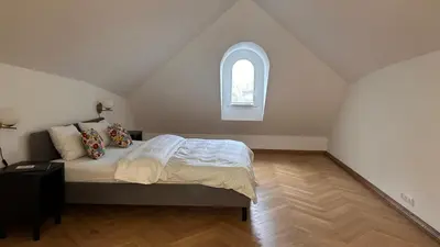 a white bedroom with a bed with a window at Vydūno apartamentai 8 in Kaunas