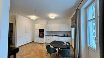 a kitchen with white cabinets and a table and chairs at Vydūno apartamentai 8 in Kaunas
