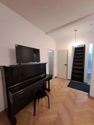 a black piano in a living room with a staircase at Vydūno apartamentai 8 in Kaunas
