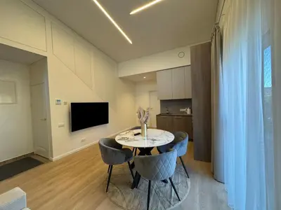a dining room with a table and chairs and a television at Ajeru Apartments in Kaunas
