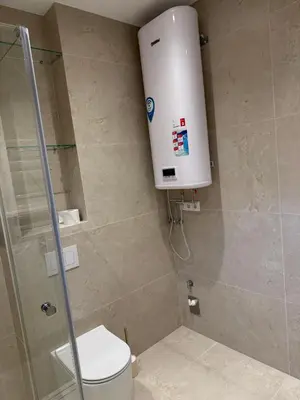 a bathroom with a shower with a toilet and a tank at Ajeru Apartments in Kaunas