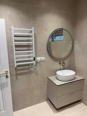 a bathroom with a round mirror and a sink at Ajeru Apartments in Kaunas