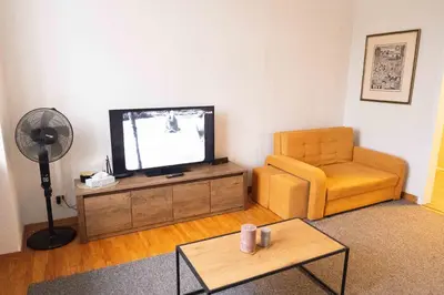a living room with a television and a chair at Vilnius Old Town Riverside Apartment in Vilnius