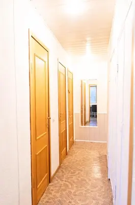 a hallway with four wooden doors and a tile floor at Vilnius Old Town Riverside Apartment in Vilnius