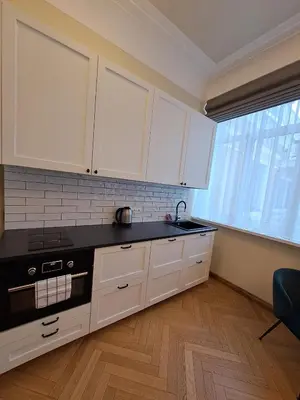 a kitchen with white cabinets and a black counter top at Vydūno apartamentai 5 in Kaunas