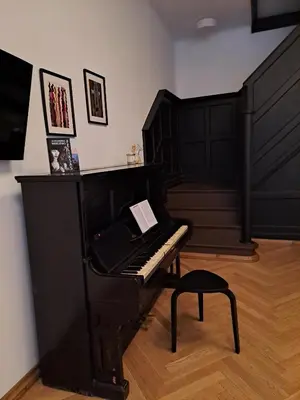 a black piano sitting in a room with a stool at Vydūno apartamentai in Kaunas
