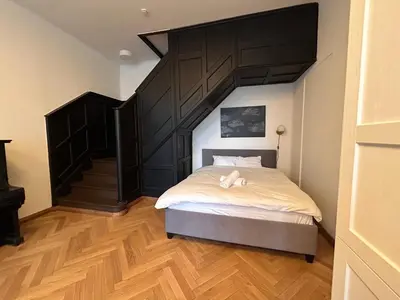 a bedroom with a large bed and a staircase at Vydūno apartamentai in Kaunas