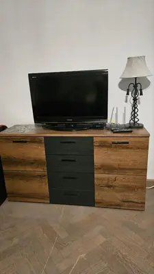 a television on top of a wooden dresser with a lamp at Dviejų kambarių butas Kauno centre in Kaunas